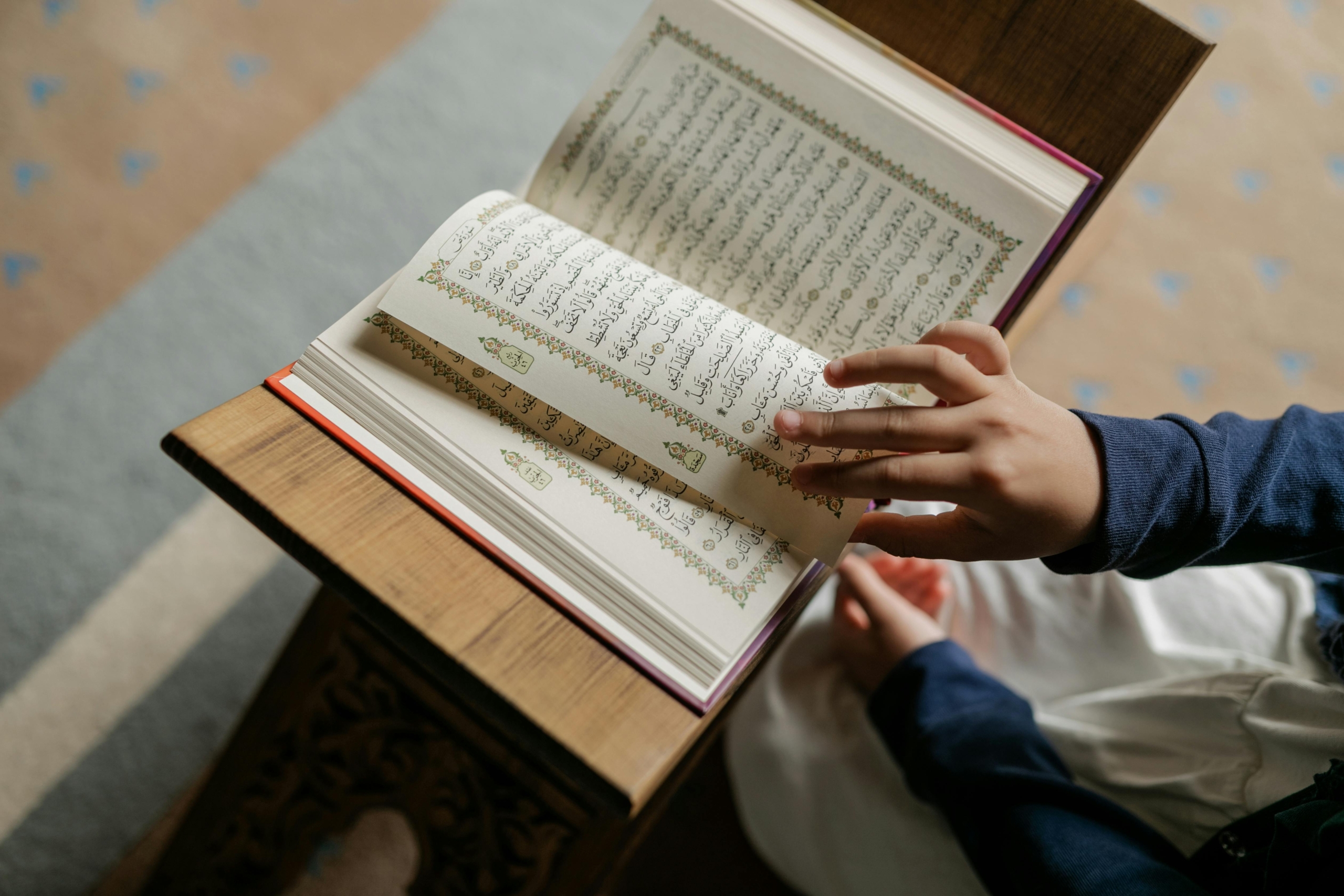 Hand eines Mädchens, das im Koran blättert